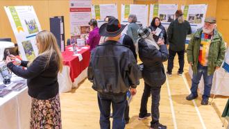 A crowd mingles surrounded by exhibits showcasing the 2026 Heritage Award Winners' accomplishments.