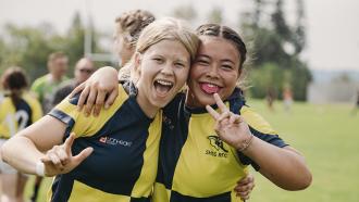 Two teen teammates in black and yellow jerseys celebrating at Telosky Park, during the 2024 BC Summer Games in Maple Ridge