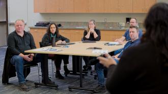 A City staff person presents to a table full of City managers.