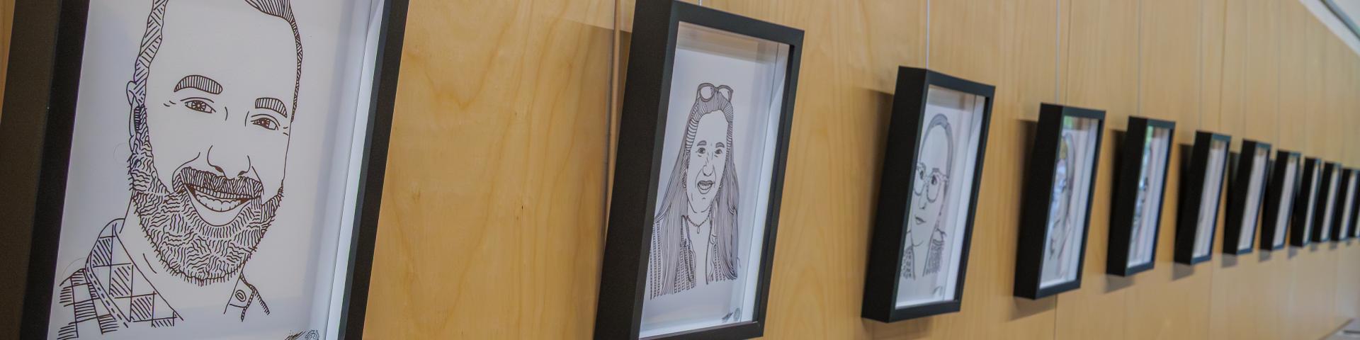 Constellation by Alex Neff; a line of black pen portraits framed and lined up on the wall of the Albion Community Centre.