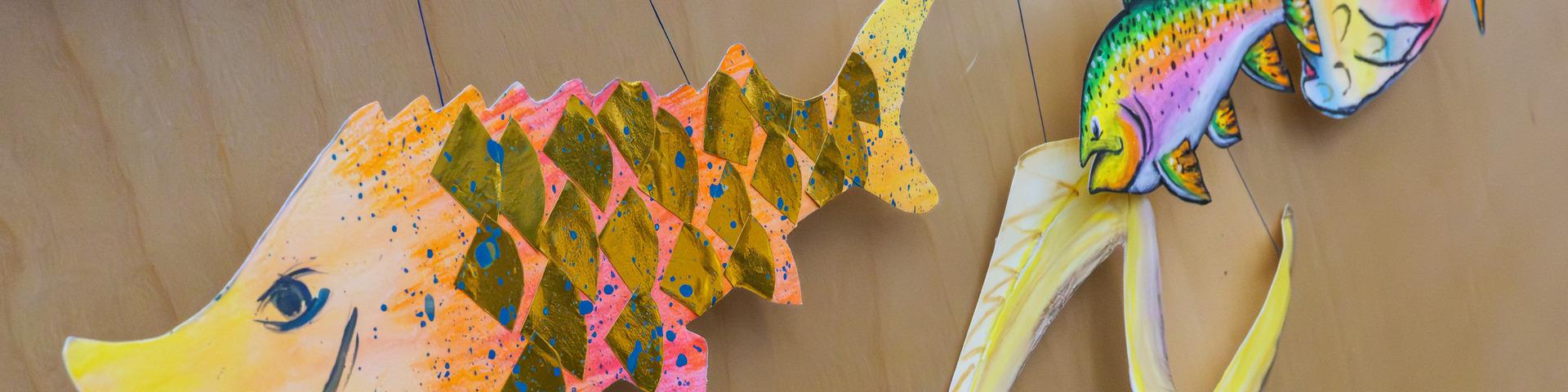 Various paper fish line a wall, smiling.