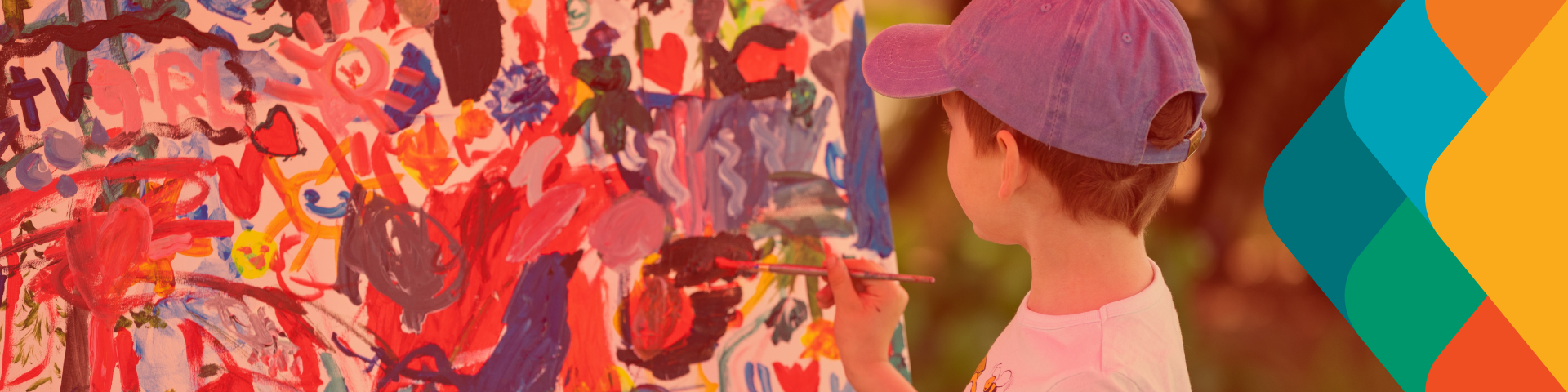 A young boy paints on a canvas outdoors.