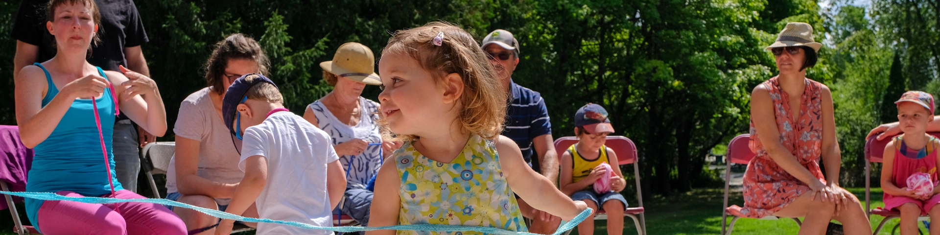 A young girl dances to the delight of several parents seated in camp chairs.
