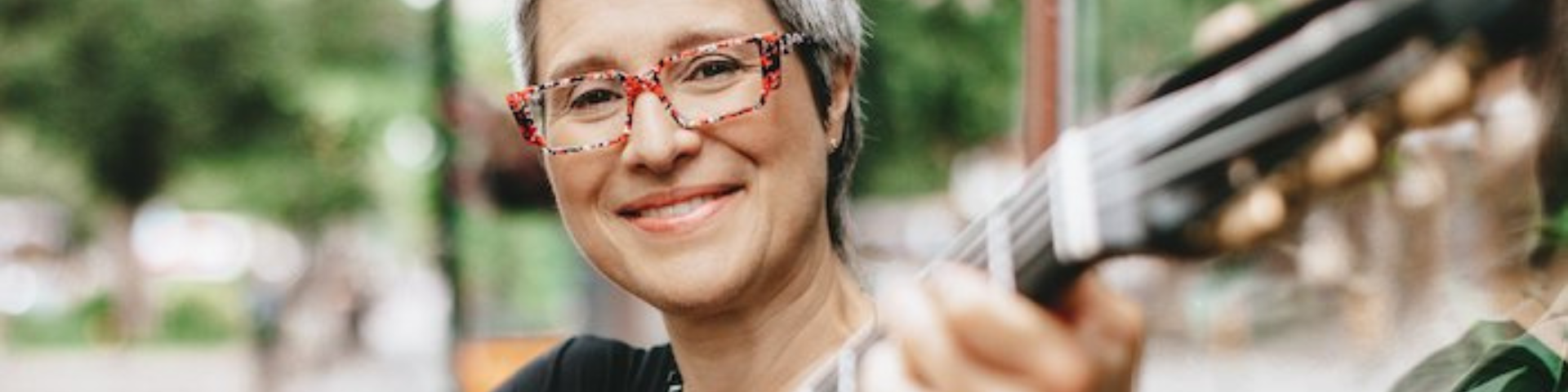 Christine Tassan smiles while playing a guitar.