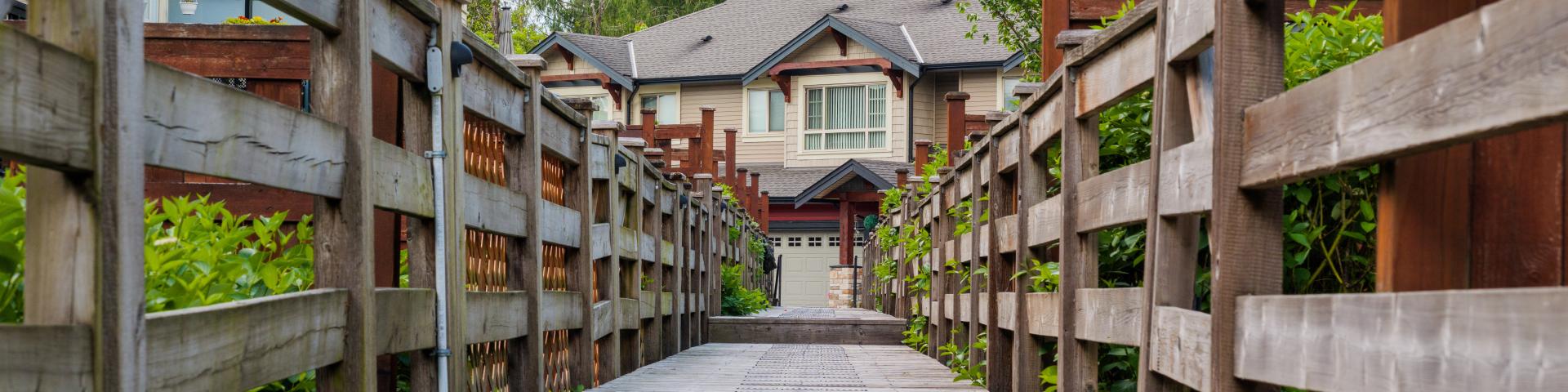 A wooden pathway leads across a gully to a set of houses.