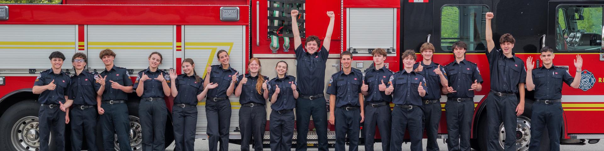 2026 Youth Fire academy graduates in uniform standing in front of a fire truck