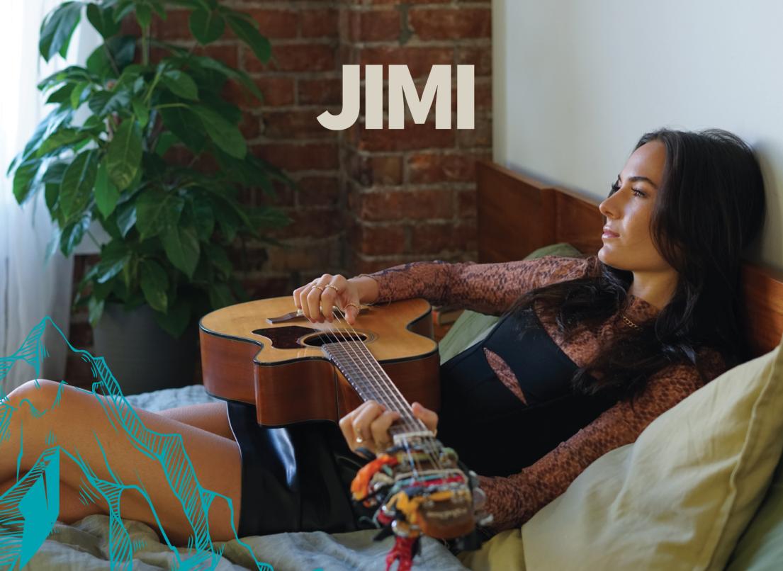 Jimi leans back on a bed with an acoustic guitar.