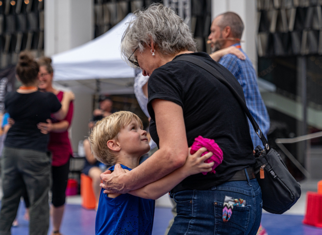 A grandmother dances with her young grandson, who holds a ball of yarn.
