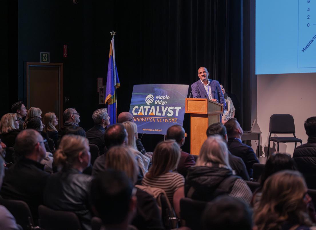 The keynote speaker addresses the crowd from a podium onstage at the 2026 Catalyst Igniter event.