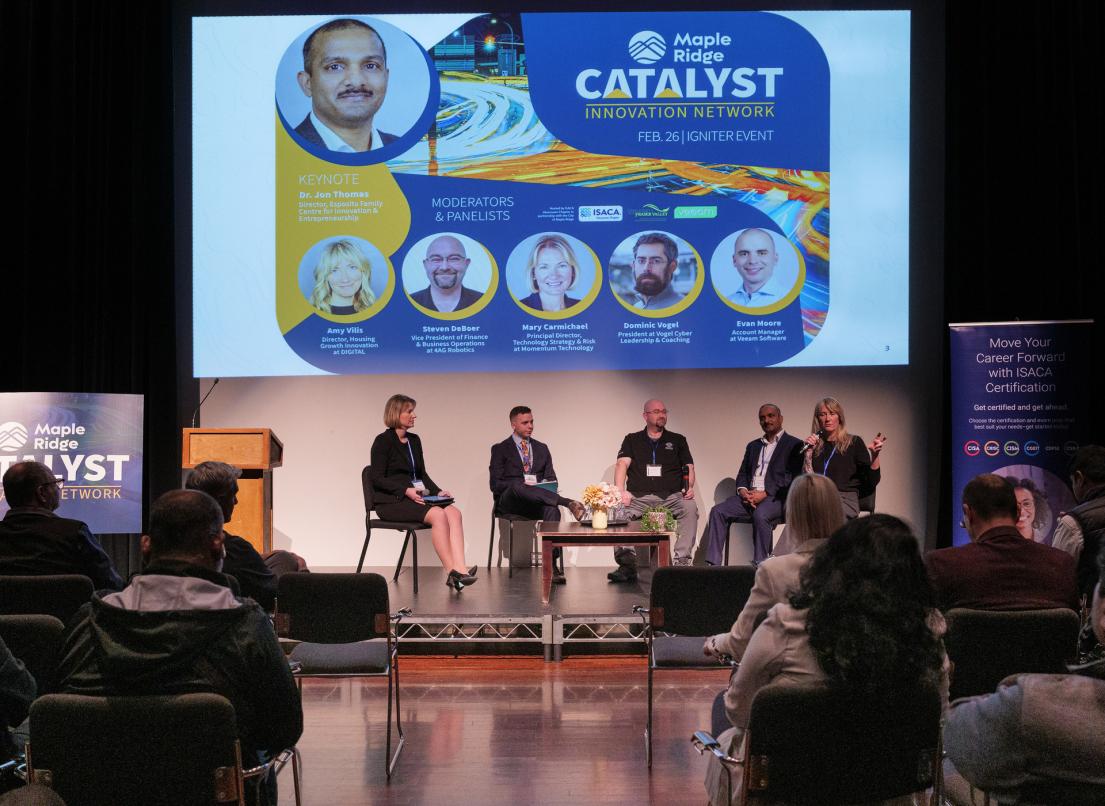 Five speakers sit on a small stage addressing the crowd at the 2026 Catalyst Igniter event.