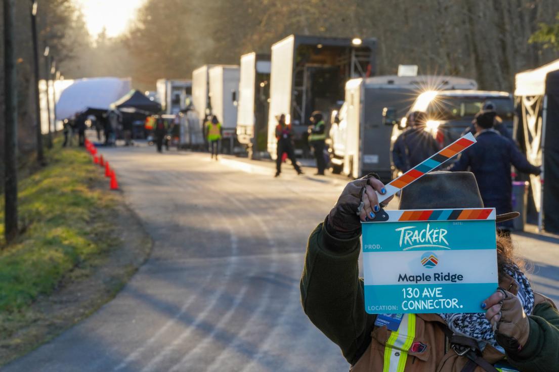 A film crew member holding a Maple Ridge film slate on the set of "Tracker" at 130 Avenue