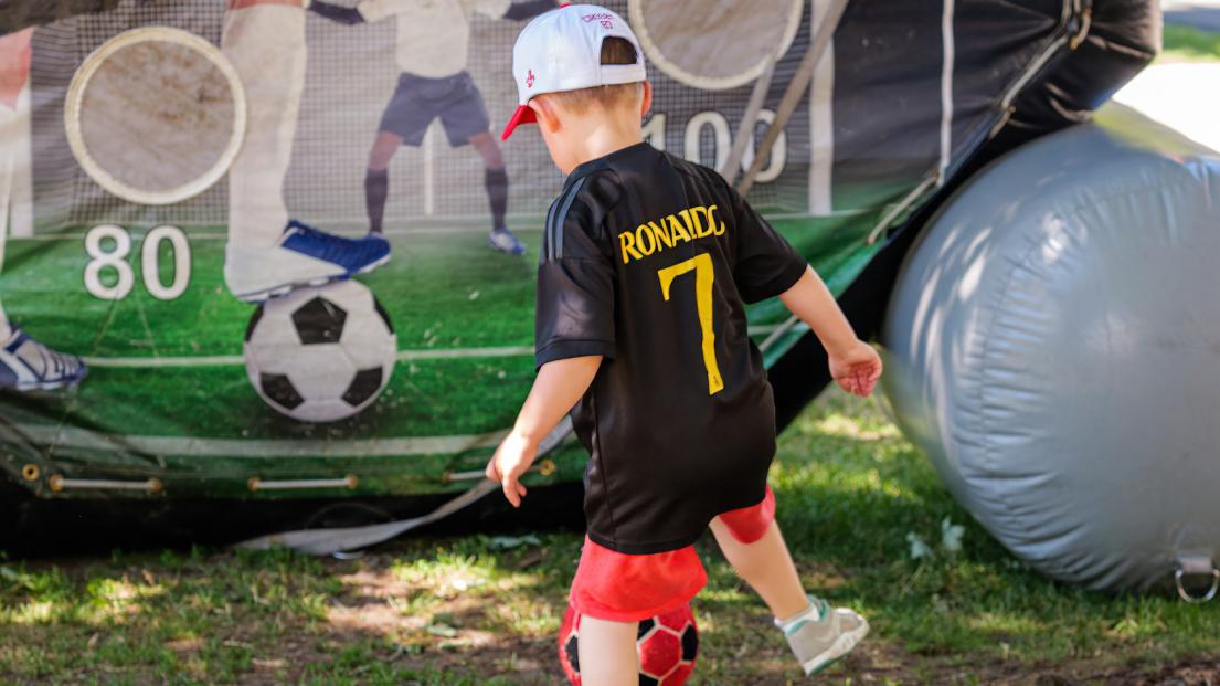 A young boy gears up to kick a red soccer ball into a target net.