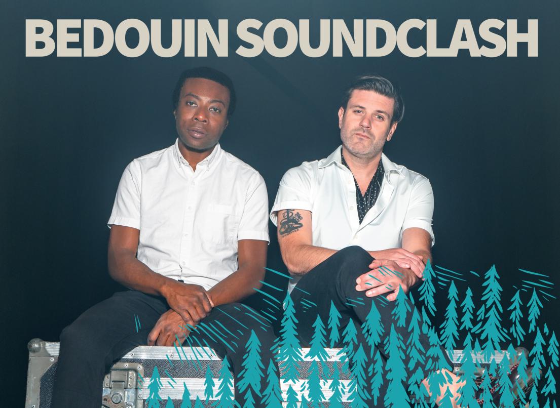 The performers of Bedouin Soundclash sit on a storage chest in matching white shirts and dark jeans. 