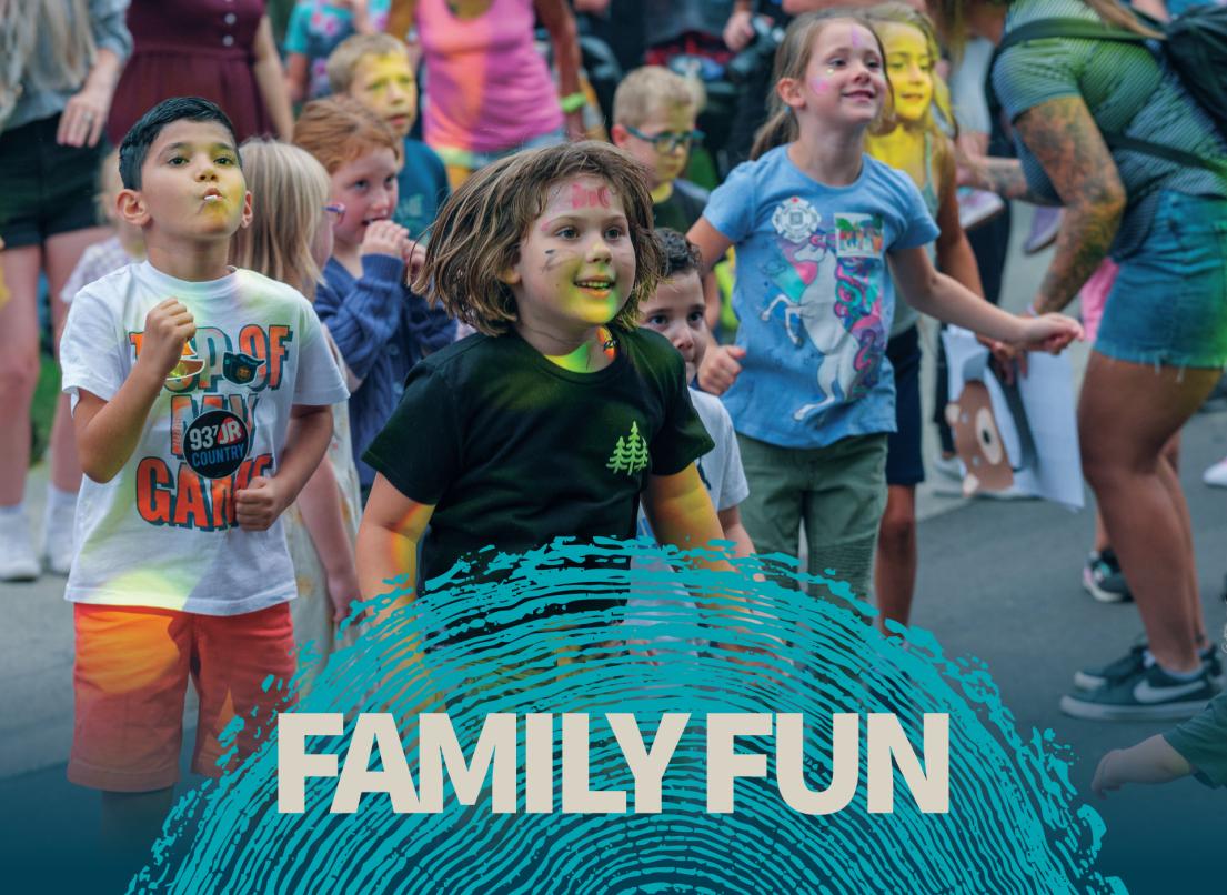 A group of kids with facepaint jump at an event.