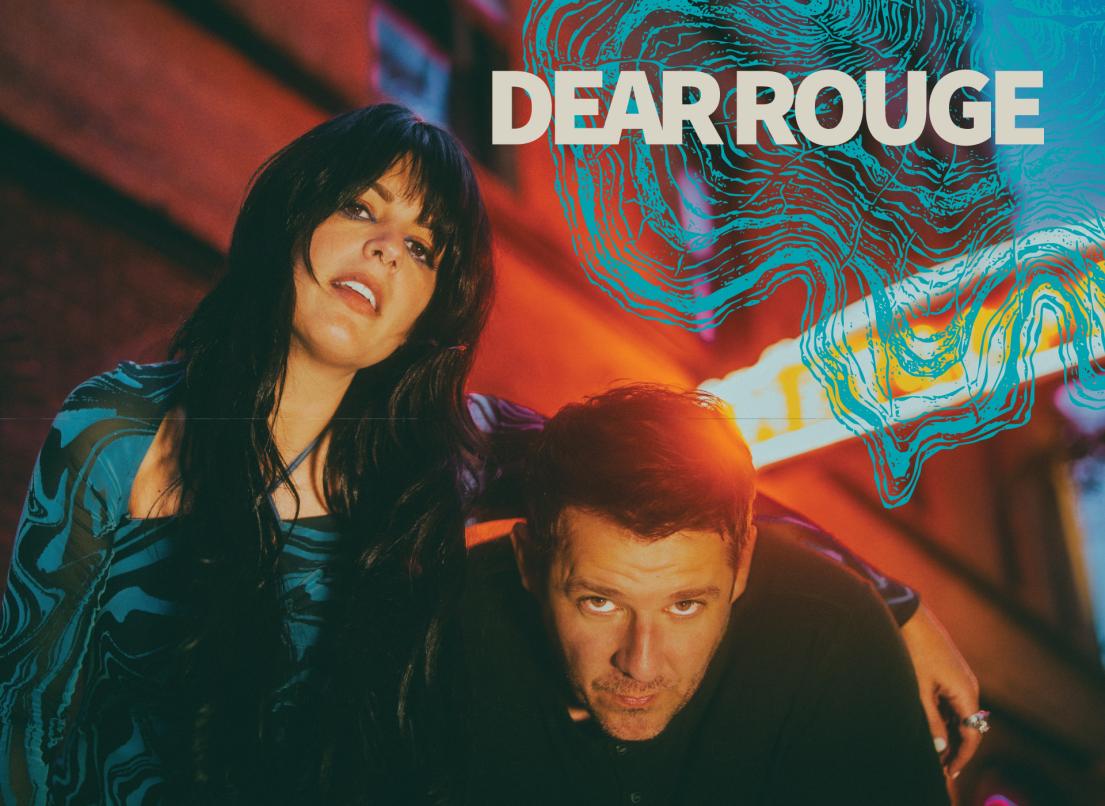 A woman slings her arm over a man as he leans down. In the upper corner is the band name, "Dear Rouge".