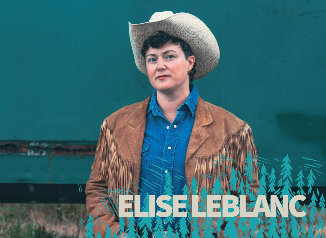 Elisa LeBlanc stands wearing a cowboy hat and leather jacket against a dark blue wall.