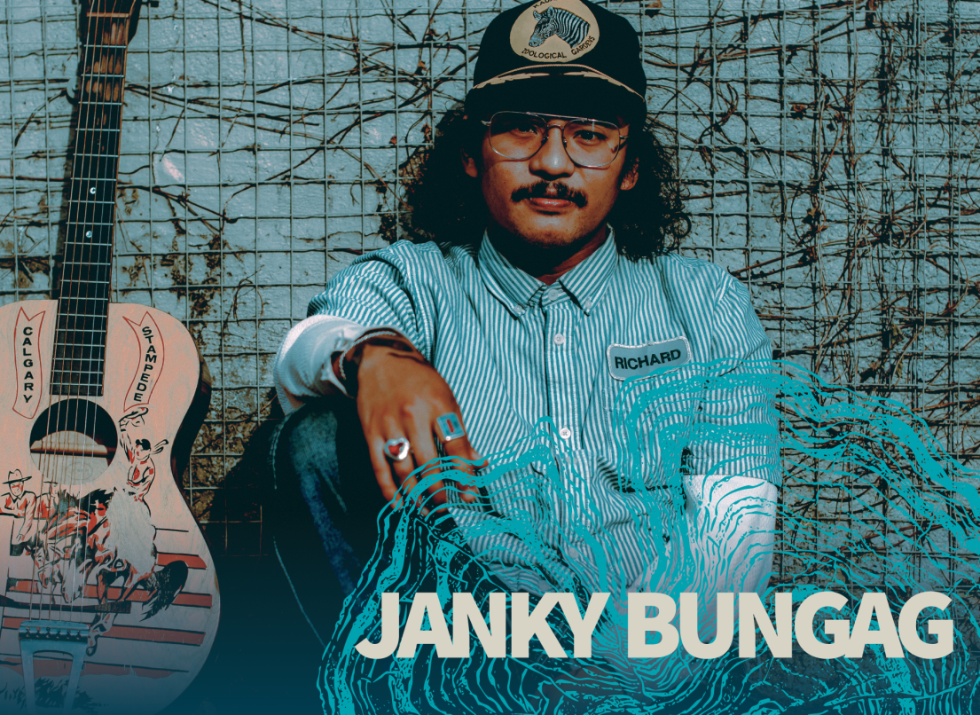 Janky Bungag sits against a wire fence next to his guitar.