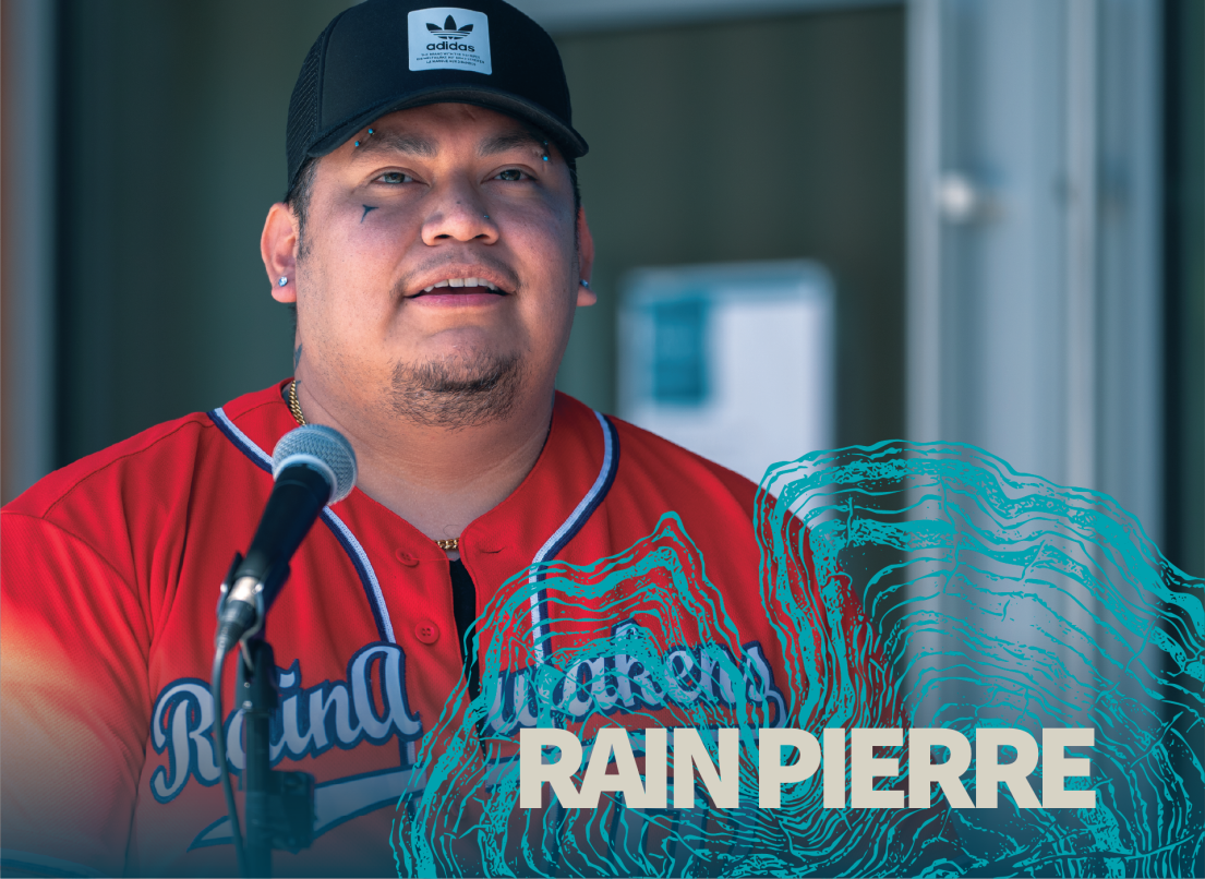 Rain Pierre wears a red sports jersey and speaks into a microphone.