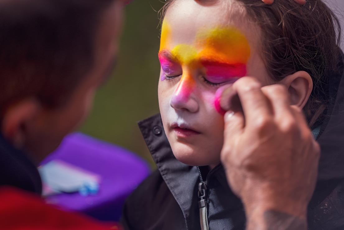A young girl closes her eyes so that she can have her face painted.