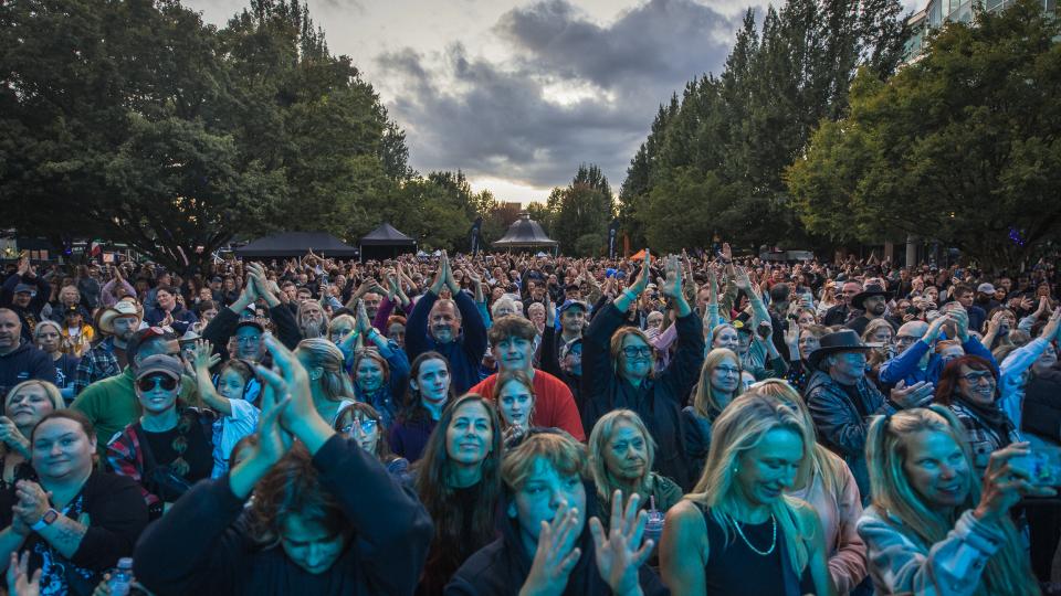 A crowd of people at Memorial Peace Park bathe in the light from the Golden Ears Stage, enjoying and anticipating the live music at the Our Neck of the Woods Festival.