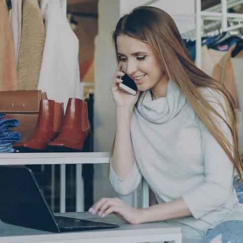 Shop owner making a phone call while using a computer