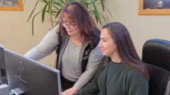 Two female city staff observe a computer screen, while one points to an item.