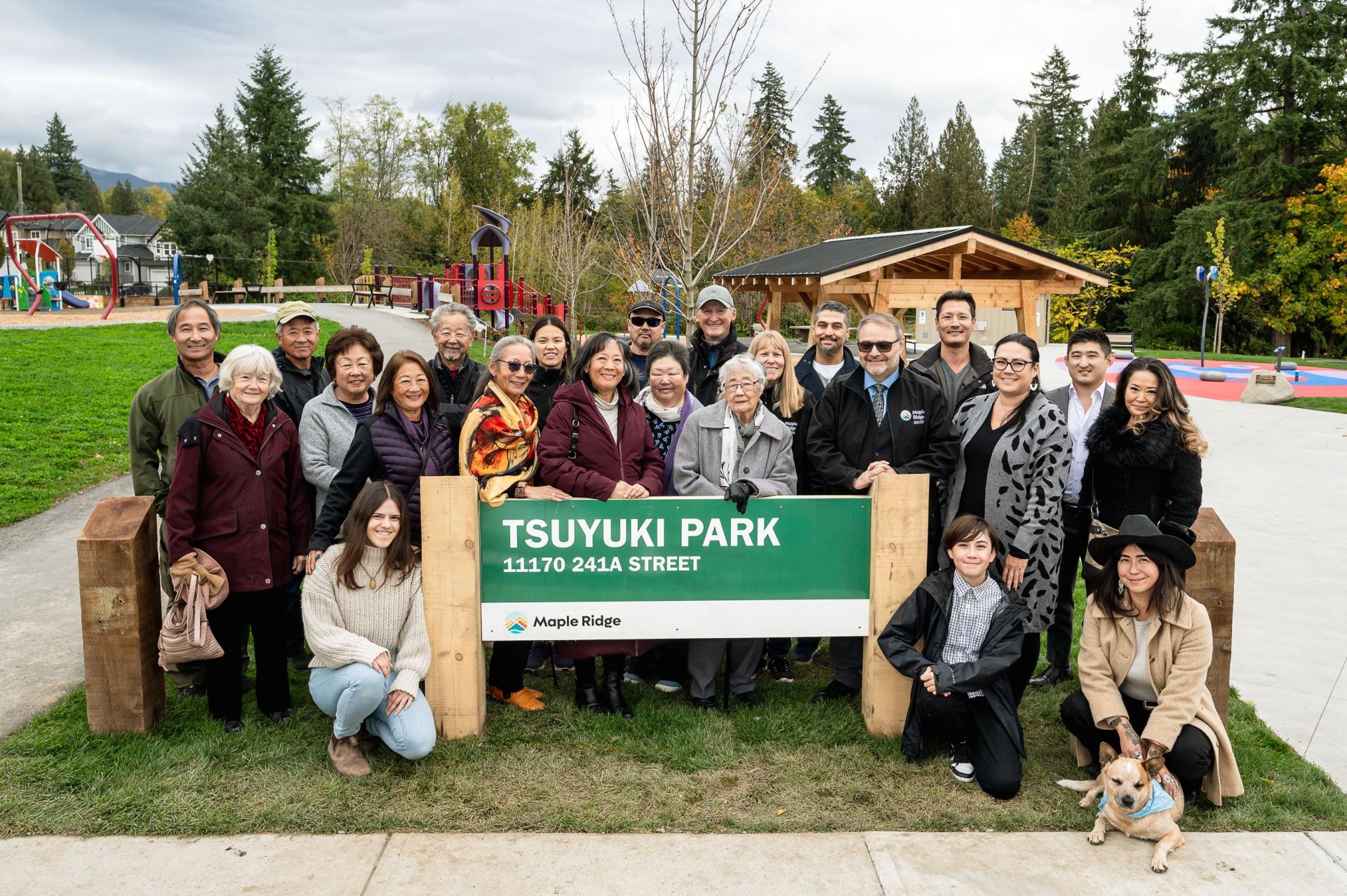 A group of people smiling in front of Tsuyuki Park sign