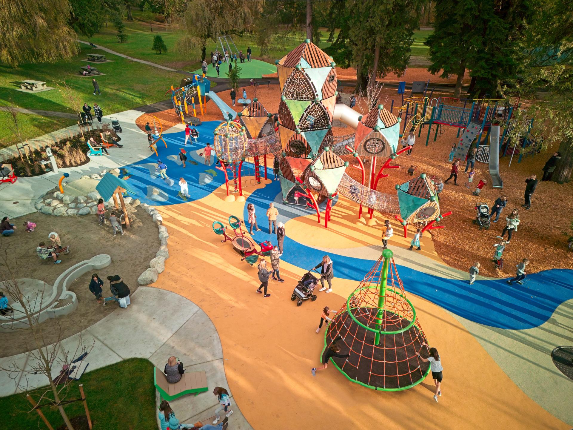 aerial photo of playground with lots of children and adults and featuring tall climbing tower 