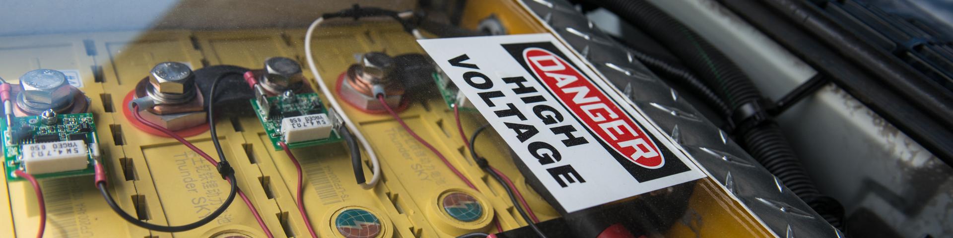 A "Danger, High Voltage" sign site above some electrical wires.