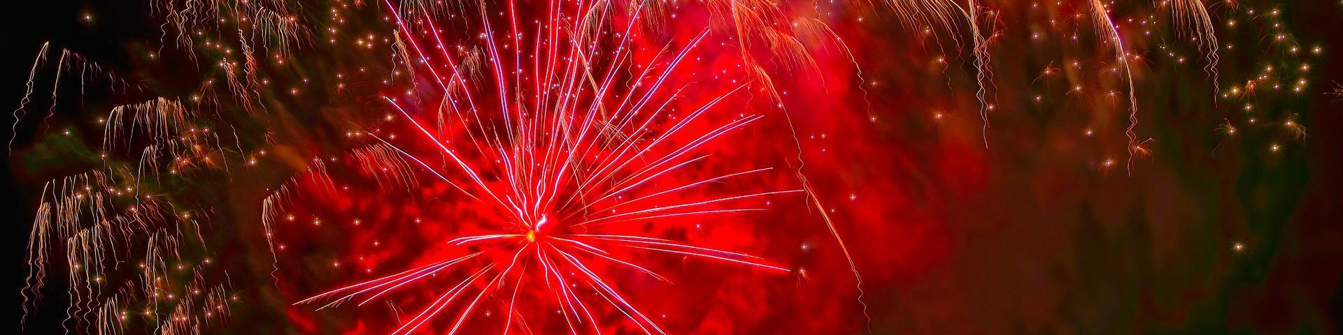 Red fireworks light up the dark night sky.