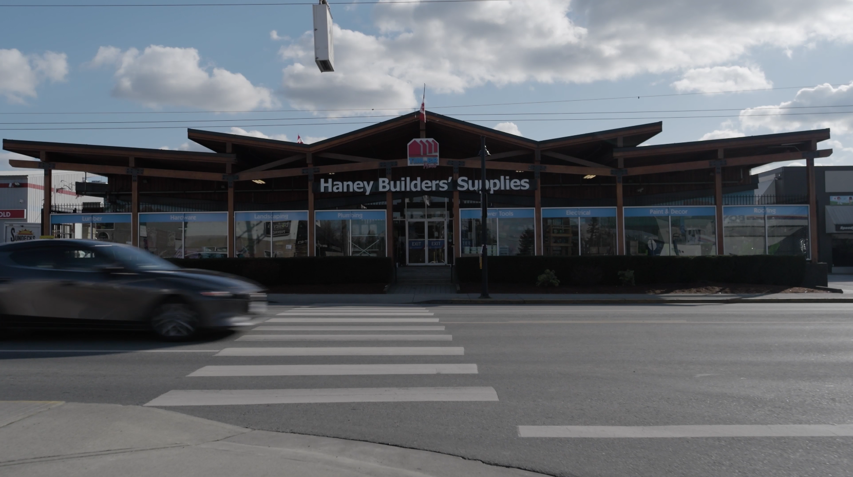 The Haney Builders' Supplies store sits in shadow, with a crosswalk on the road in front of it.