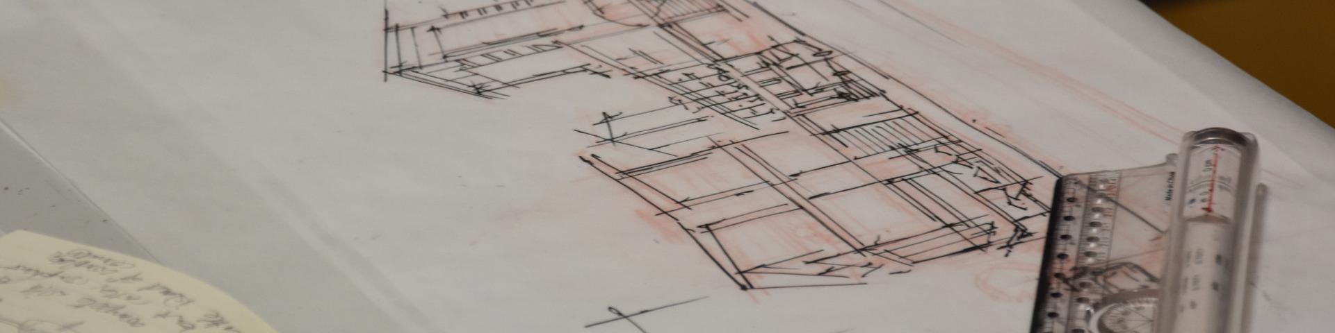 A set of architectural drawings laid on a table next to a ruler.