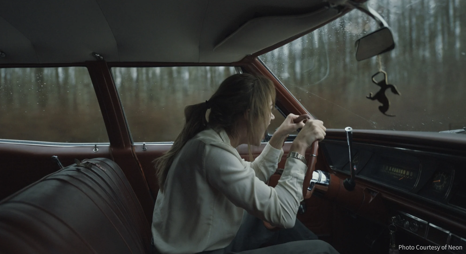 A still image from the movie "Longlegs" depicting a woman screaming in her vehicle as she drives down the street