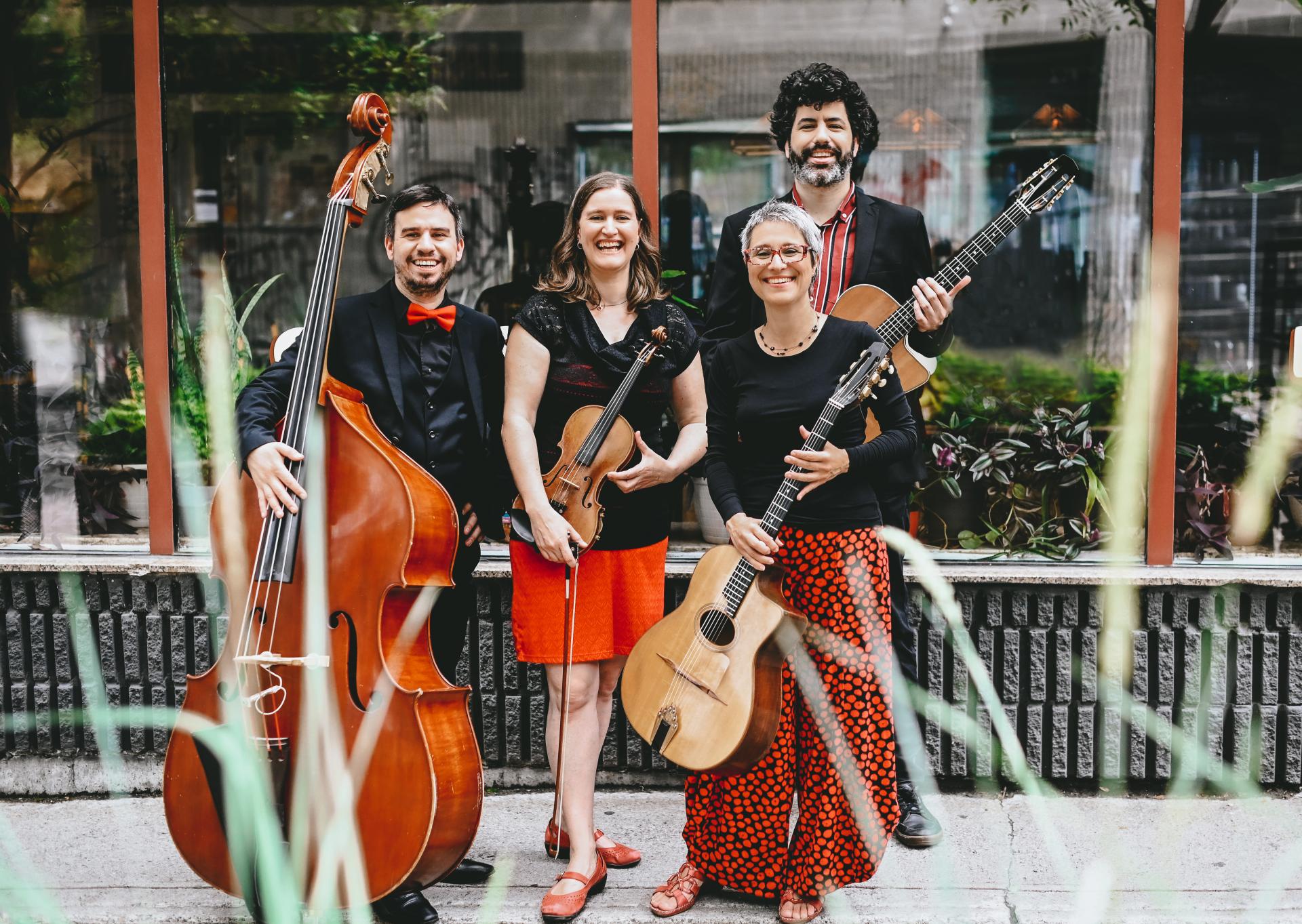 Christine Tassan et Les Imposteurs pose in from of a store with their various stringed instruments, including a guitar, violin and cello. 