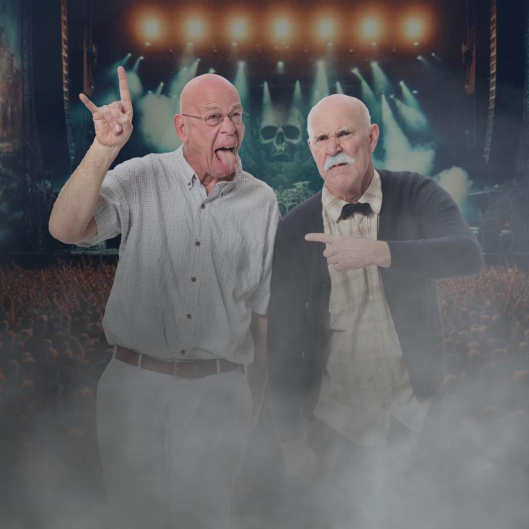 Performer Rob Gee holds up his hand in a "rock on" symbol, and sticks out his tongue while and Jonathon Paterson points to him with a displeased expression.