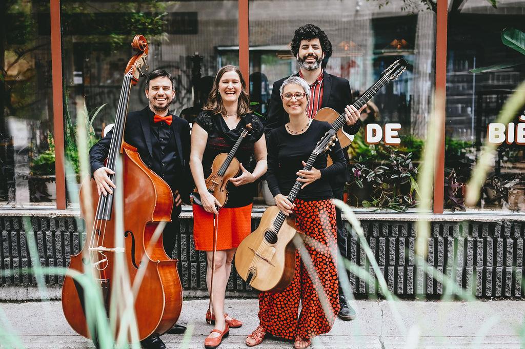 Christine Tassan et Les Imposteurs pose in from of a store with their various stringed instruments, including a guitar, violin and cello.