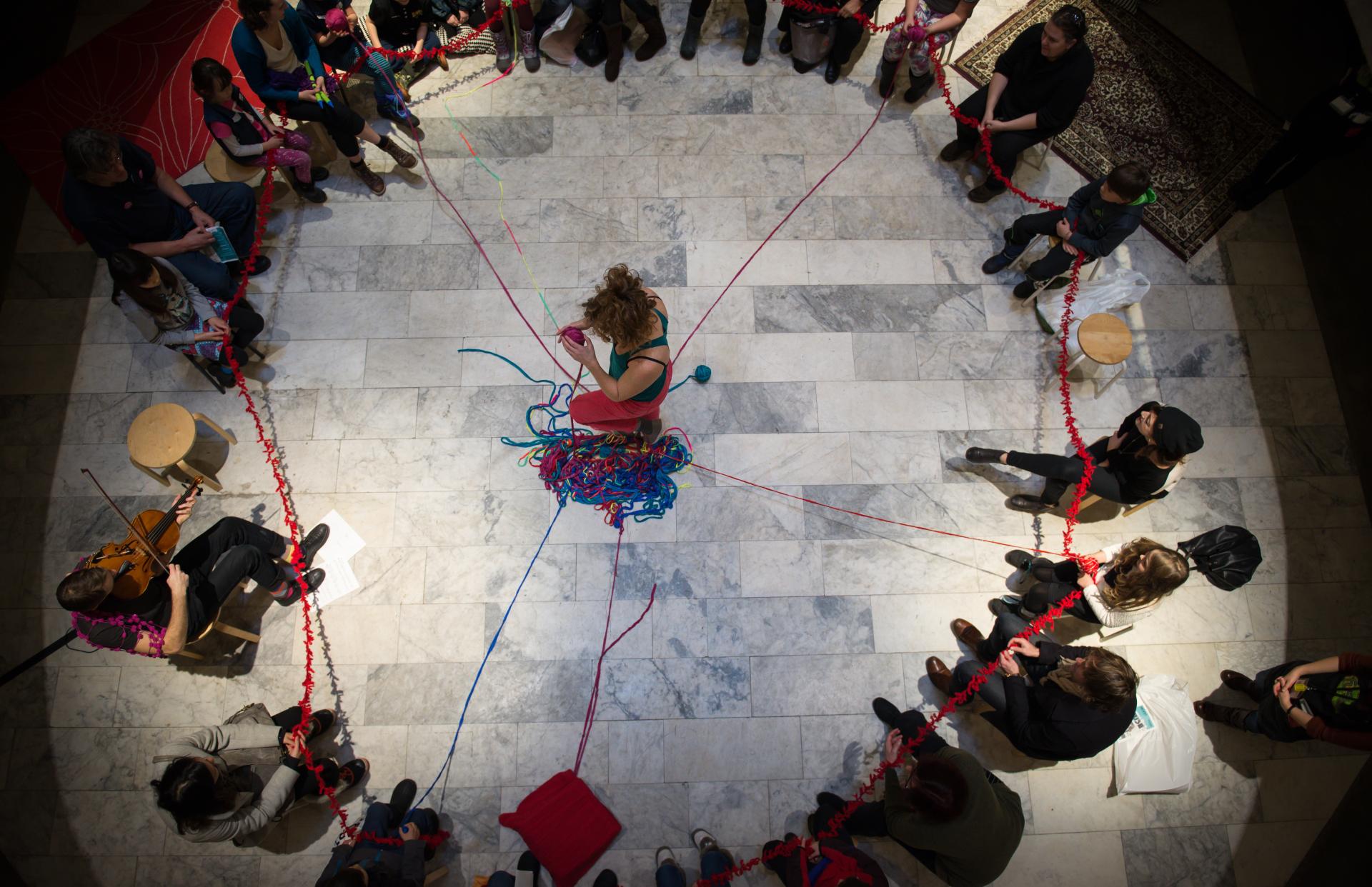 Circle of people holding pieces of yarn