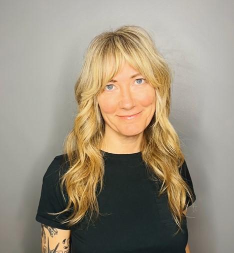 Amy Vilis smiles at the camera while wearing a black tee-shirt.