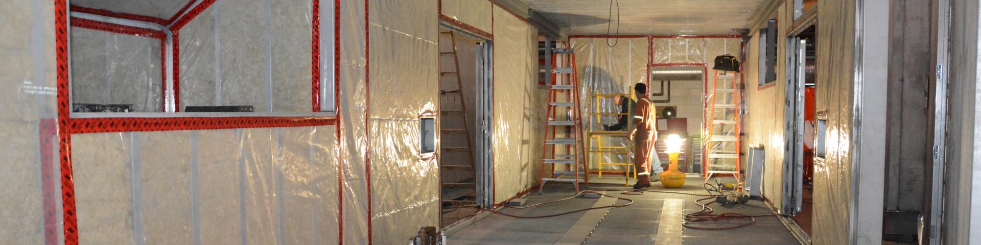 Two men converse while working on an mid-construction basement.