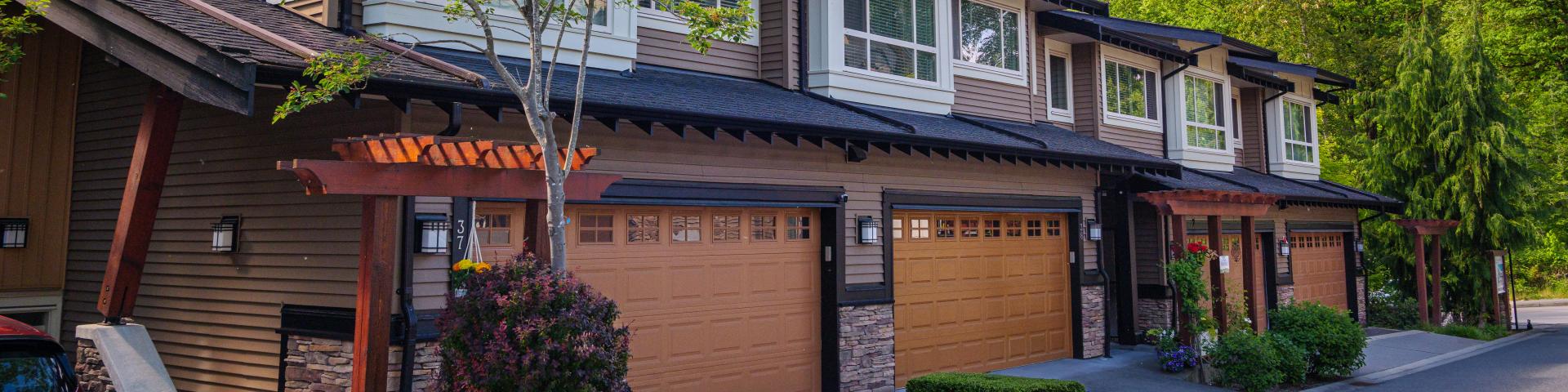 A set of brown rowhouse garages lead out to an alleyway.