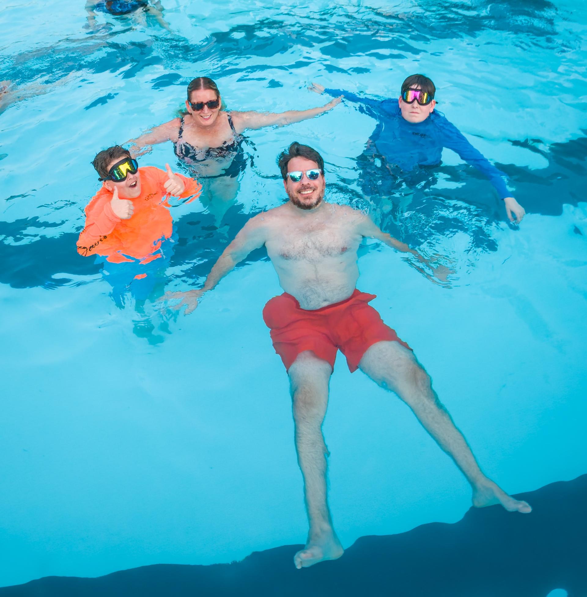family in pool smiling at camera 