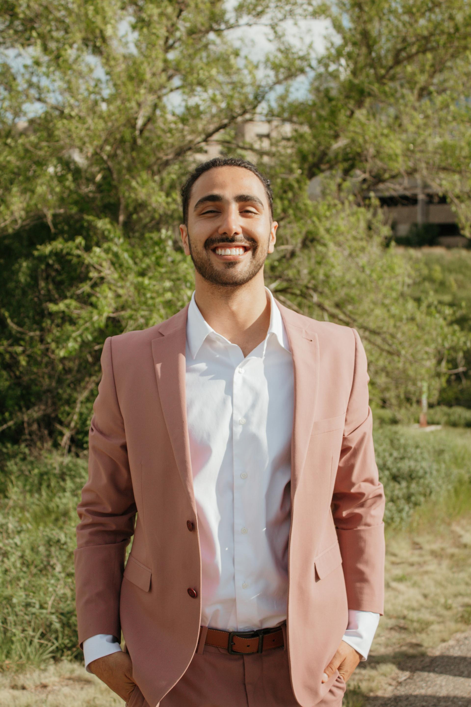 Fred Yazdini smiles at that camera, standing outside in a brown suit.