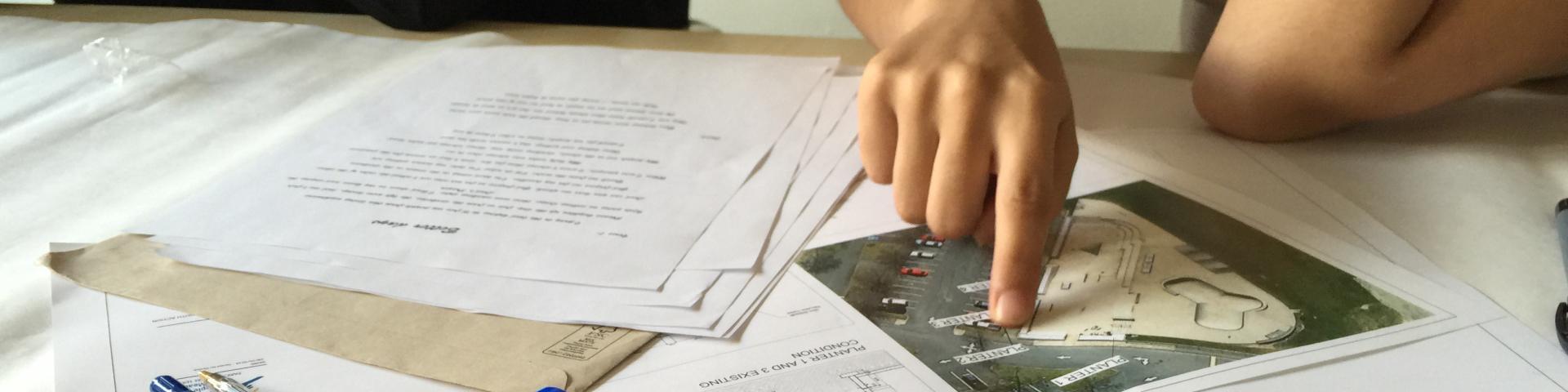 A woman points to a specific part of a graphical overhead civic planning document..