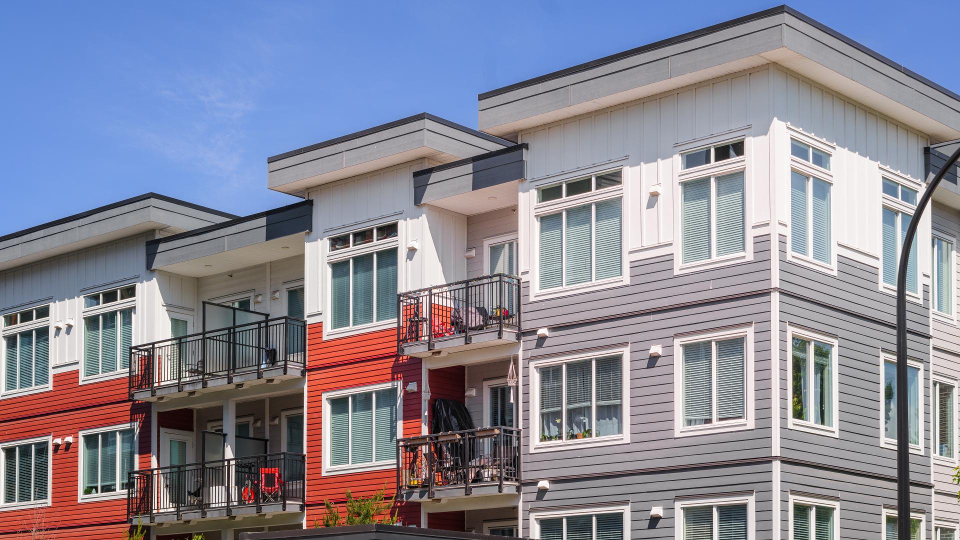 An apartment building with red, grey and white side detailing.