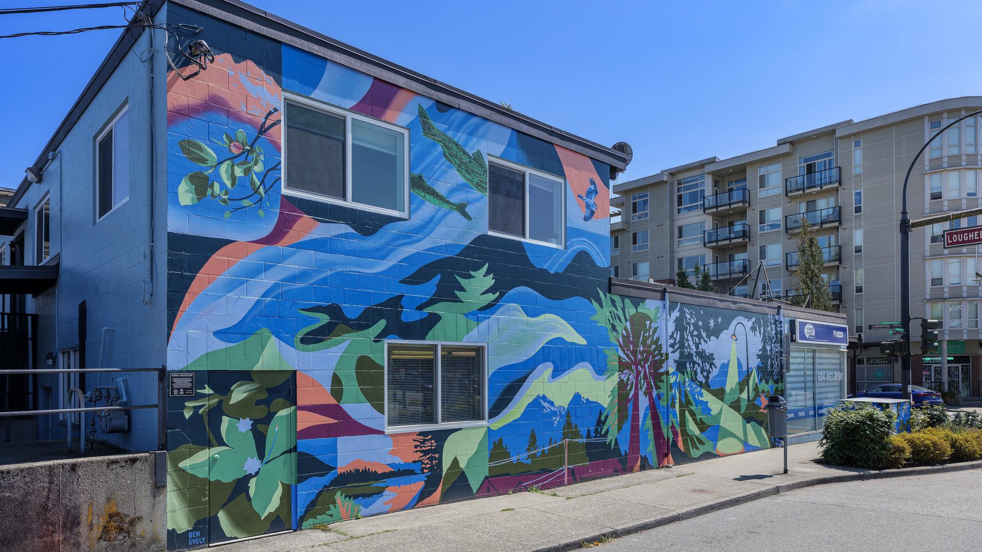 A colourful mural with blues, greens, and pale reds and pinks depicts the Golden Ears mountains, salmon, pine trees, and a street light.