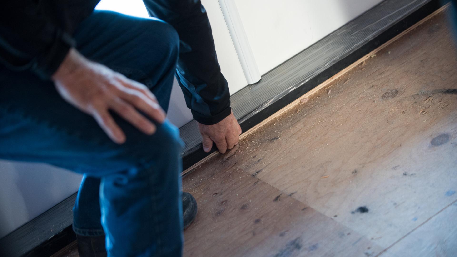 An inspector reached down to investigate the installation of the bottom of a door.