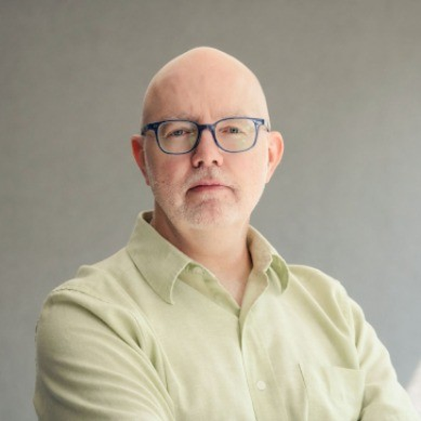 Keith Ippel looks directly at the camera while wearing a pale yellow-green collared shirt.